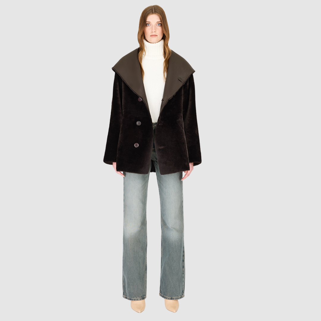 The CHEREZ Jacket is a modern mid-length hooded silhouette crafted in chocolate nappa leather shearling. Designed with drop shoulders, it offers dual-fit versatility with a tailored regular fit on the nappa side and a relaxed fit when reversed to the plush wool-out side. An exaggerated convertible hood drapes effortlessly across the shoulders as a shawl-like collar when unbuttoned, while a single-breasted button closure delivers a clean, minimalist finish. 