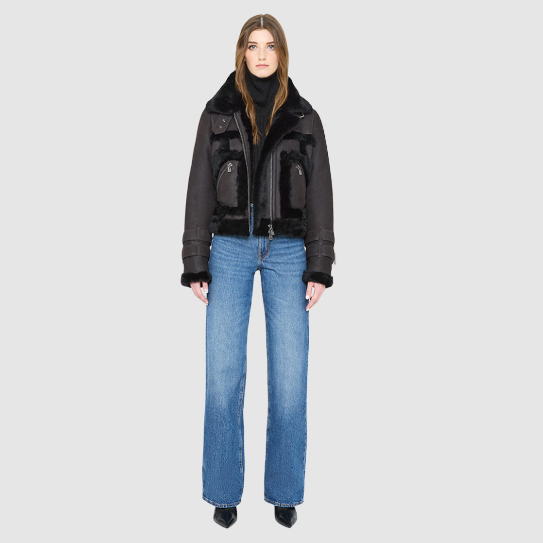 The DOLL Jacket is a heritage-inspired cropped shearling moto crafted from java semi suede leather with curly&nbsp;wool seam detailing for modern texture and dimension. Its regular shoulder and cropped silhouette create a sleek, contemporary fit, while buckle detailing on the collar and cuffs adds signature moto edge. Functional exterior and interior zip pockets and a front zip closure make DOLL as practical as it is stylish, perfect for après-ski layering or urban winter looks.