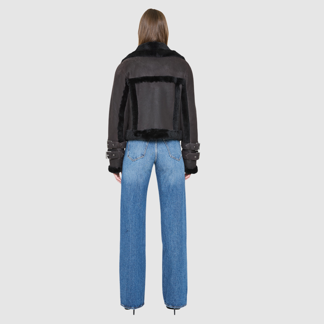 The DOLL Jacket is a heritage-inspired cropped shearling moto crafted from java semi suede leather with curly&nbsp;wool seam detailing for modern texture and dimension. Its regular shoulder and cropped silhouette create a sleek, contemporary fit, while buckle detailing on the collar and cuffs adds signature moto edge. Functional exterior and interior zip pockets and a front zip closure make DOLL as practical as it is stylish, perfect for après-ski layering or urban winter looks.