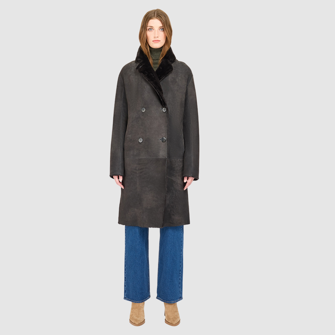 The ELLE Coat is a heritage-inspired oversized reversible shearling piece crafted in a black vintage suede ironed wool teddy. Designed to transition seamlessly from smooth suede to plush wool-out texture, this versatile style blends timeless tailoring with modern après-ski elegance. A slight drop shoulder, double-breasted button closure, and back vent add structure to its oversized silhouette. Functional single welt pockets on the suede side and slash pockets on the ironed wool side 