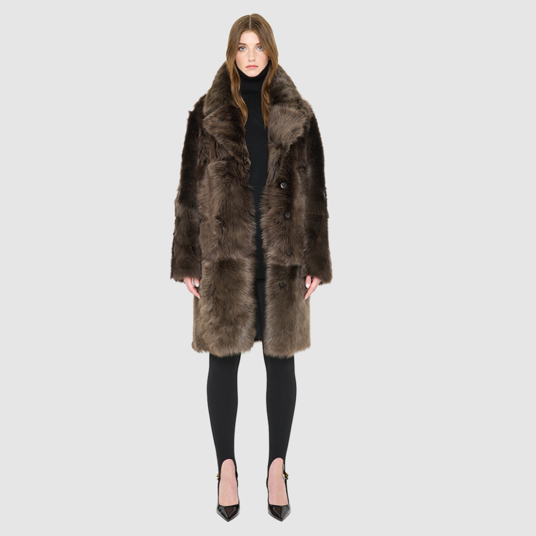 The JOY Jacket is a heritage-inspired reversible outerwear piece crafted in carbon suede shearling. Designed to flip seamlessly from plush oversized teddy to sleek suede, it offers versatile styling for both après-ski sophistication and everyday winter elegance. With a drop shoulder, large notch collar, and oversized silhouette, JOY combines comfort with modern edge. Functional slash side pockets on the teddy side and single welt pockets on the suede side, along with a front button closure, complete this lu