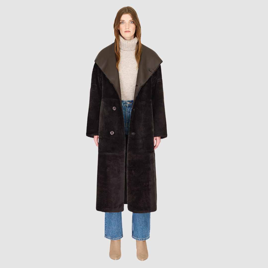 The MELONI Chocolate Silky Nappa Ironed Wool Jacket merges contemporary luxury with versatile, reversible design. Crafted from smooth nappa leather and plush ironed wool, this oversized coat offers two distinctive looks in one—sleek nappa for a modern finish and textured wool for cozy warmth. Its oversized hood converts to a dramatic shawl collar, while drop shoulders and a relaxed silhouette ensure comfort and ease of layering. Functional pull-through pockets and a refined button closure complete the coat