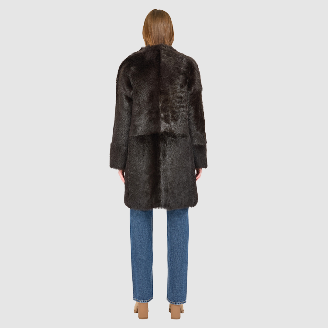 The ALLORA Jacket is a luxury reversible shearling teddy crafted in chocolate silky Toscana for a rich and modern finish. Designed as a collarless oversized silhouette, it effortlessly flips from plush wool-out shearling to a sleek nappa skin-out jacket, offering two looks in one. With its generous fit through the shoulders, arms, and torso, ALLORA balances comfort and style. Functional slash side pockets on both sides and a front snap closure complete this elevated women’s reversible shearling jacket.