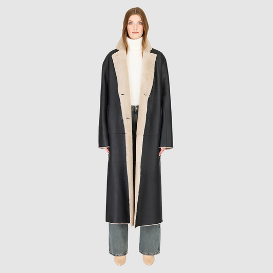 The DANIELLE Duster is a statement in heritage-inspired luxury and modern versatility. Crafted in black beige nappa and plush iron wool shearling, this reversible oversized coat transitions effortlessly from sleek leather to cozy teddy texture. Its elongated silhouette is enhanced with a slight drop shoulder, back vent, and double-breasted button closure, creating timeless elegance with functional edge. Practical single welt pockets on the suede side and slash pockets on the wool side