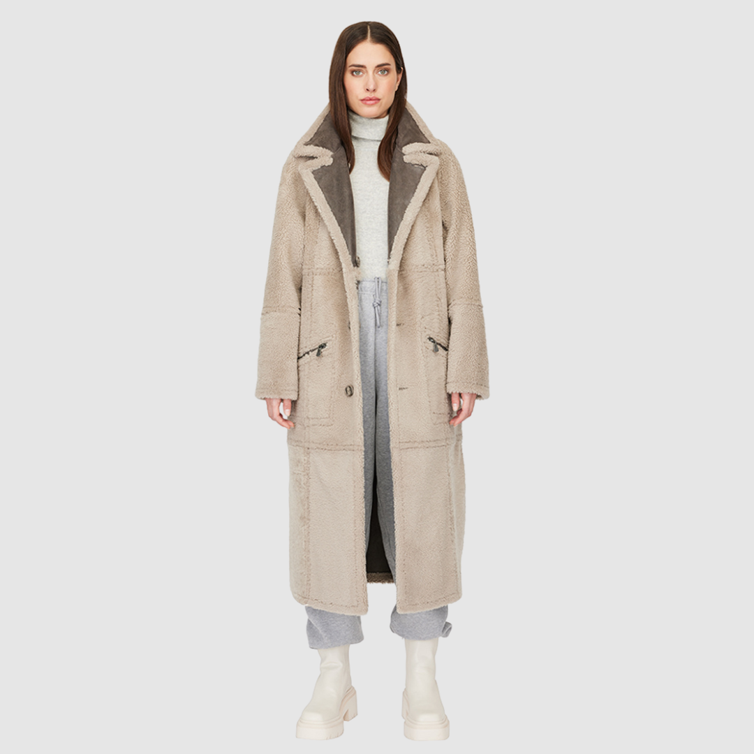 The DANIELLE Duster is a statement in heritage-inspired luxury and modern versatility. Crafted in Macassar nappa leather and plush curly wool shearling, this reversible oversized coat transitions effortlessly from sleek leather to cozy teddy texture. Its elongated silhouette is enhanced with a slight drop shoulder, back vent, and double-breasted button closure, creating timeless elegance with functional edge. Practical single welt pockets on the nappa side and slash pockets on the wool side