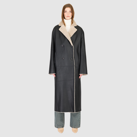 The DANIELLE Duster is a statement in heritage-inspired luxury and modern versatility. Crafted in black beige nappa and plush iron wool shearling, this reversible oversized coat transitions effortlessly from sleek leather to cozy teddy texture. Its elongated silhouette is enhanced with a slight drop shoulder, back vent, and double-breasted button closure, creating timeless elegance with functional edge. Practical single welt pockets on the suede side and slash pockets on the wool side
