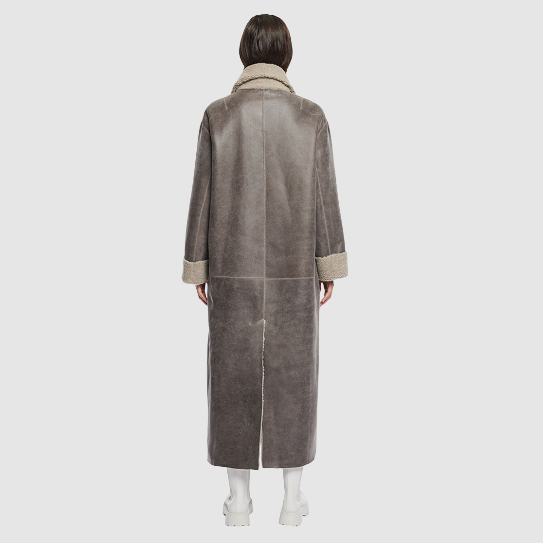The DANIELLE Duster is a statement in heritage-inspired luxury and modern versatility. Crafted in Macassar nappa leather and plush curly wool shearling, this reversible oversized coat transitions effortlessly from sleek leather to cozy teddy texture. Its elongated silhouette is enhanced with a slight drop shoulder, back vent, and double-breasted button closure, creating timeless elegance with functional edge. Practical single welt pockets on the nappa side and slash pockets on the wool side