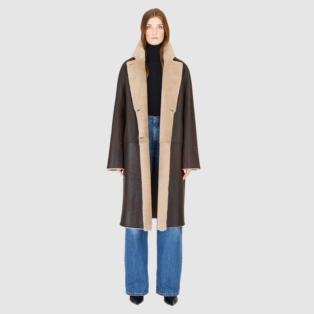 The ELLE Coat is a heritage-inspired oversized reversible shearling piece crafted in a oxen brown nappa ironed wool teddy. Designed to transition seamlessly from smooth suede to plush wool-out texture, this versatile style blends timeless tailoring with modern après-ski elegance. A slight drop shoulder, double-breasted button closure, and back vent add structure to its oversized silhouette. Functional single welt pockets on the suede side and slash pockets on the ironed wool side.