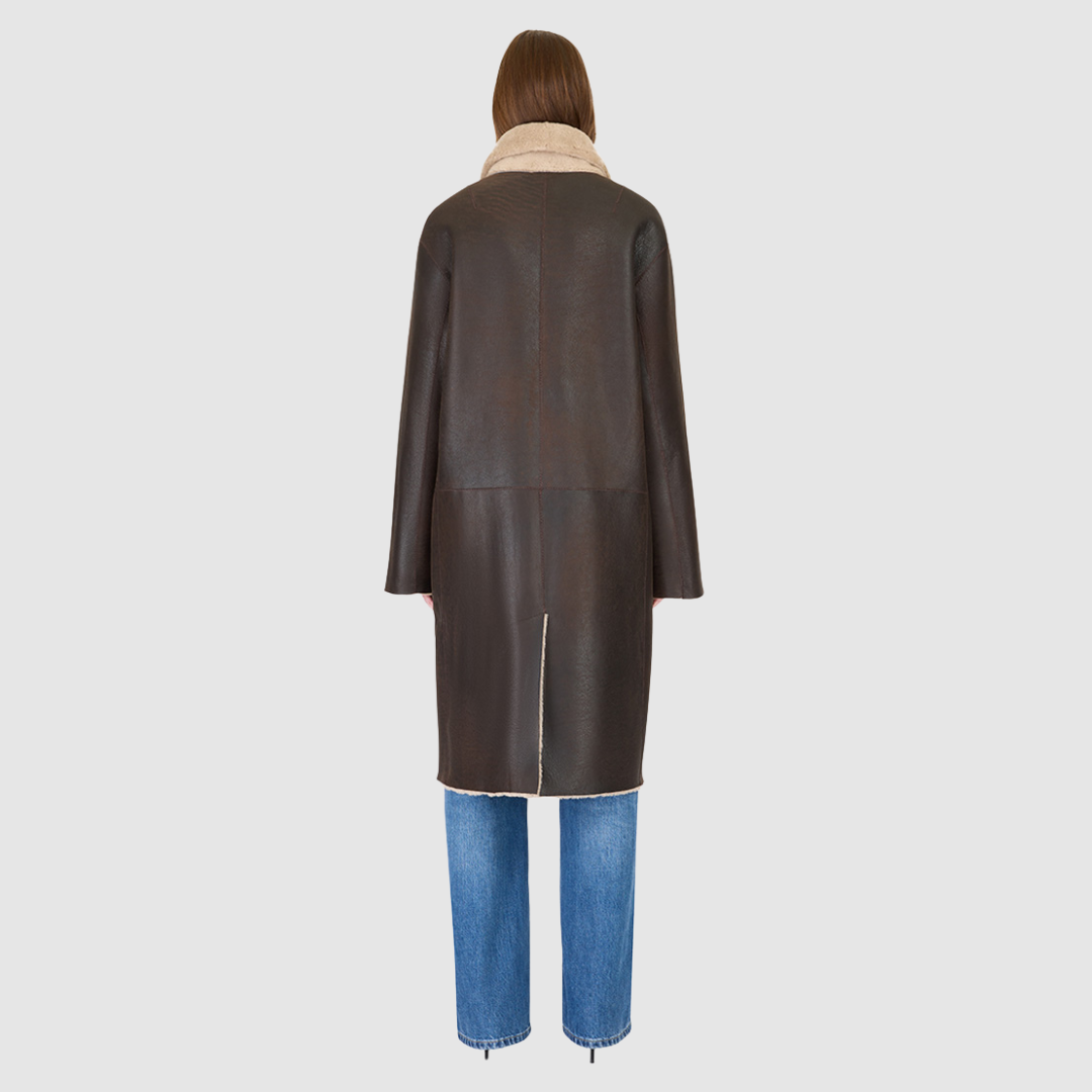The ELLE Coat is a heritage-inspired oversized reversible shearling piece crafted in a oxen brown nappa ironed wool teddy. Designed to transition seamlessly from smooth suede to plush wool-out texture, this versatile style blends timeless tailoring with modern après-ski elegance. A slight drop shoulder, double-breasted button closure, and back vent add structure to its oversized silhouette. Functional single welt pockets on the suede side and slash pockets on the ironed wool side.