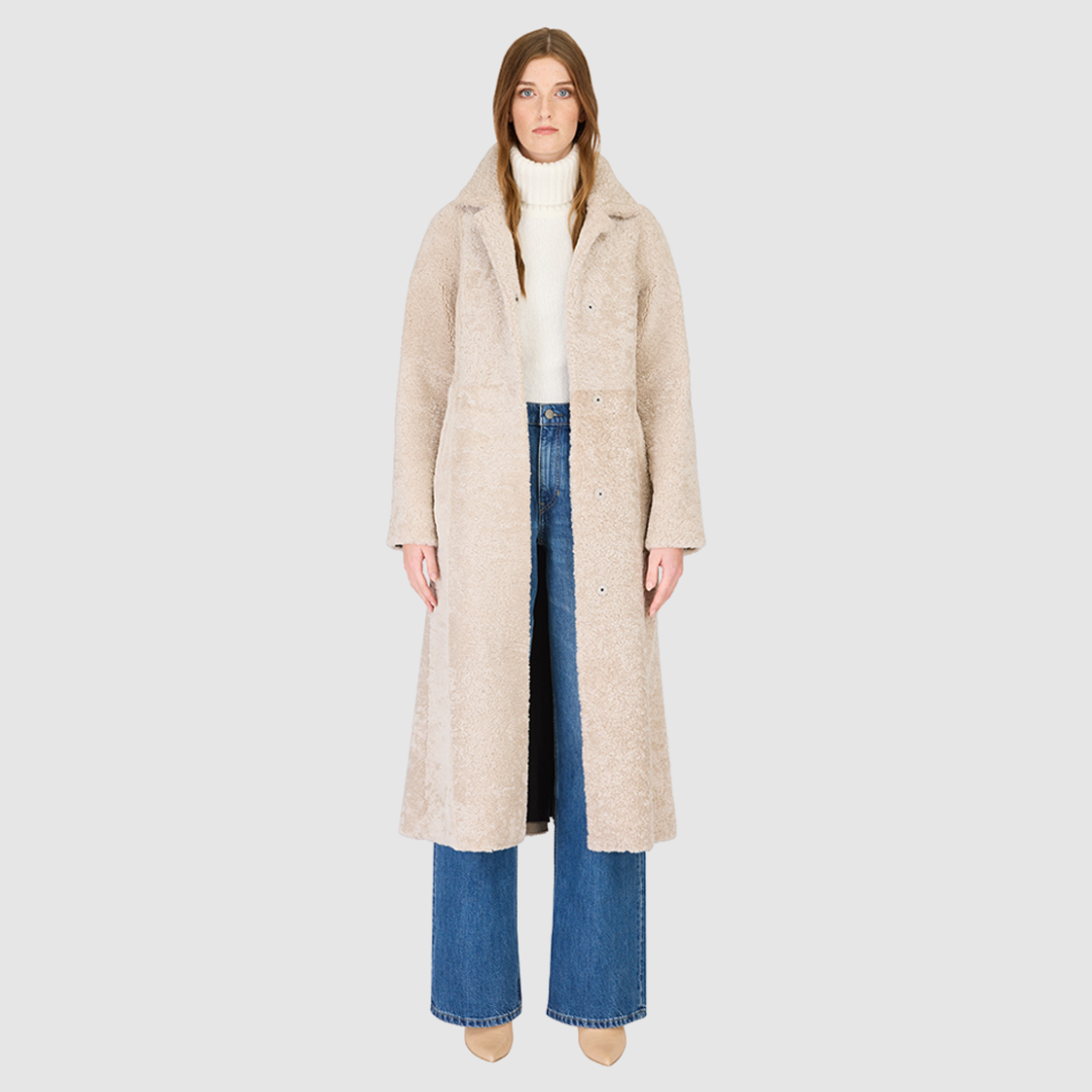 The EMBER Coat is a heritage-inspired wool-out curly mouton wrap crafted in rich black for timeless sophistication. Designed with a regular shoulder and fitted torso, it offers a flattering silhouette while maintaining comfort and warmth. A small curly wool notch collar, slash side pockets, and a front snap with tie belt closure combine function with elevated style. Fully lined for luxury, EMBER is perfect for après-ski evenings or refined everyday winter wear.