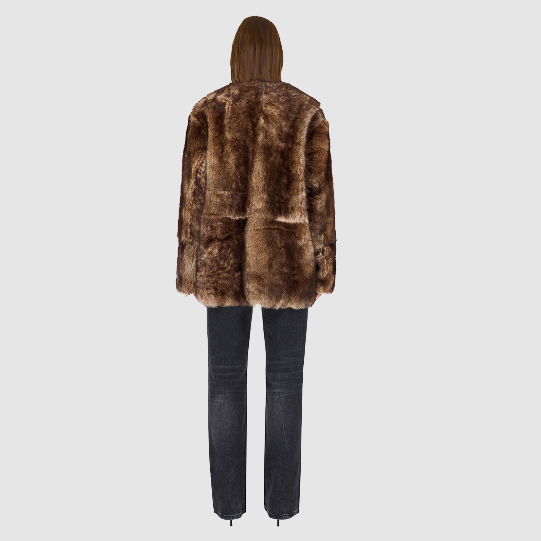 The Illumi Burma Nappa Toscana Jacket redefines modern luxury with its reversible, collarless design. Crafted from supple nappa leather and plush Toscana shearling, this oversized teddy-inspired silhouette offers two distinct looks in one. The wool-out side showcases rich texture and warmth, while the smooth nappa side delivers a sleek, refined finish. Designed for versatility and comfort, it features patch pockets on both sides and a clean snap-front closure—perfect for transitioning from city dressing to 