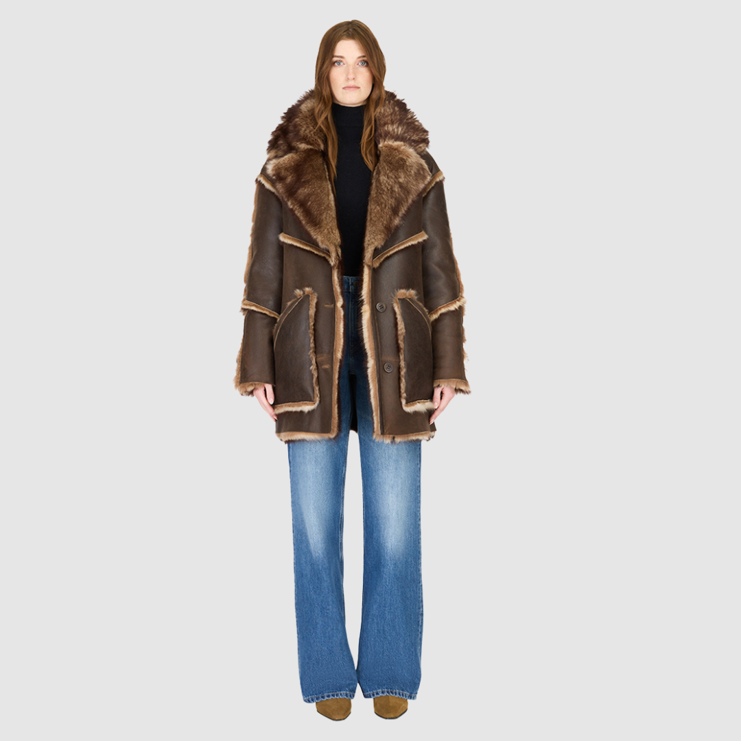 The LUREEN Coat is a luxury reversible semi-suede outerwear piece crafted in Burma Toscana. Designed to flip seamlessly from smooth semi-suede to plush Toscana wool teddy, it offers versatile styling for cold-weather layering. The wool-out Toscana seam detailing on the semi-suede side, combined with a drop shoulder and relaxed fit through shoulders, arms, and torso, creates effortless volume and structure. An oversized Toscana notch collar, patch pockets on both sides, and a front button closure complete th