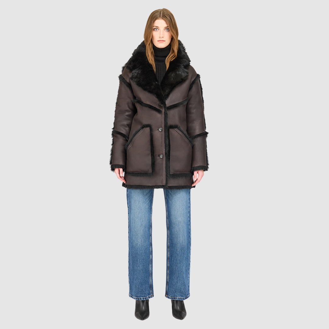 The LUREEN Coat is a luxury reversible semi-suede outerwear piece crafted in Java Toscana. Designed to flip seamlessly from smooth semi-suede to plush Toscana wool teddy, it offers versatile styling for cold-weather layering. The wool-out Toscana seam detailing on the semi-suede side, combined with a drop shoulder and relaxed fit through shoulders, arms, and torso, creates effortless volume and structure. An oversized Toscana notch collar, patch pockets on both sides, and a front button closure.