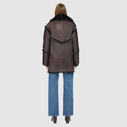 The LUREEN Coat is a luxury reversible semi-suede outerwear piece crafted in Java Toscana. Designed to flip seamlessly from smooth semi-suede to plush Toscana wool teddy, it offers versatile styling for cold-weather layering. The wool-out Toscana seam detailing on the semi-suede side, combined with a drop shoulder and relaxed fit through shoulders, arms, and torso, creates effortless volume and structure. An oversized Toscana notch collar, patch pockets on both sides, and a front button closure.