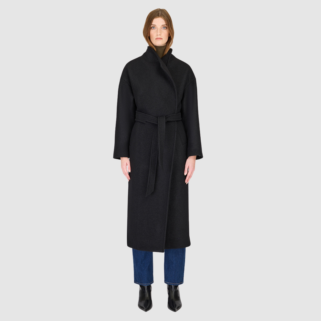 The Petra Taupe Boiled Wool Coat is crafted from premium Italian boiled wool, offering warmth, structure, and effortless sophistication. Designed as an oversized wrap silhouette, it features a tie belt for adjustable styling, drop shoulders for a relaxed drape, and a modern stand collar. Finished with discreet single welt side pockets, this coat balances timeless tailoring with contemporary ease—perfect for versatile cold-weather layering.