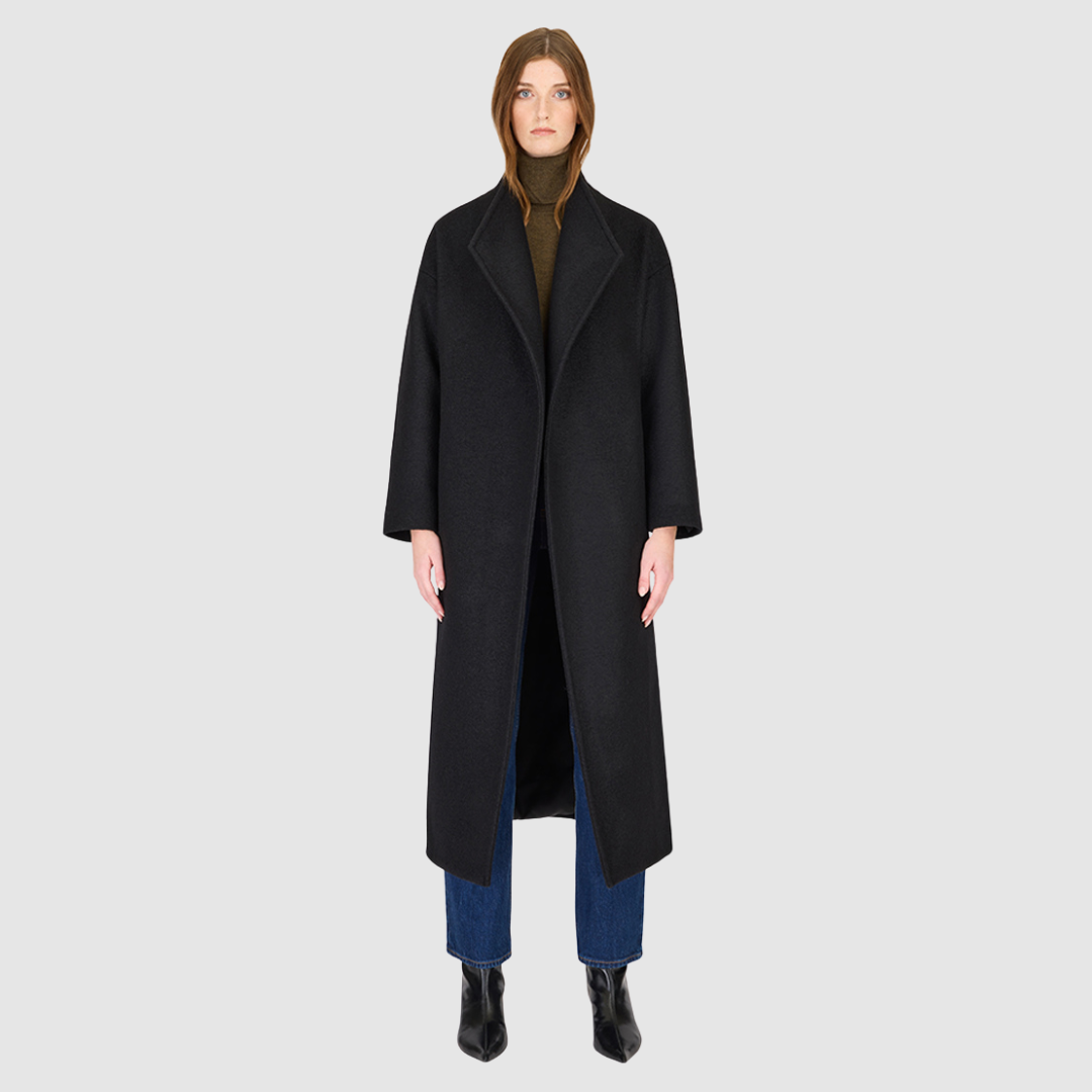 The Petra Taupe Boiled Wool Coat is crafted from premium Italian boiled wool, offering warmth, structure, and effortless sophistication. Designed as an oversized wrap silhouette, it features a tie belt for adjustable styling, drop shoulders for a relaxed drape, and a modern stand collar. Finished with discreet single welt side pockets, this coat balances timeless tailoring with contemporary ease—perfect for versatile cold-weather layering.