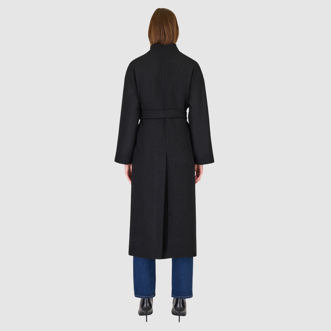 The Petra Taupe Boiled Wool Coat is crafted from premium Italian boiled wool, offering warmth, structure, and effortless sophistication. Designed as an oversized wrap silhouette, it features a tie belt for adjustable styling, drop shoulders for a relaxed drape, and a modern stand collar. Finished with discreet single welt side pockets, this coat balances timeless tailoring with contemporary ease—perfect for versatile cold-weather layering.