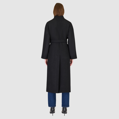 The Petra Taupe Boiled Wool Coat is crafted from premium Italian boiled wool, offering warmth, structure, and effortless sophistication. Designed as an oversized wrap silhouette, it features a tie belt for adjustable styling, drop shoulders for a relaxed drape, and a modern stand collar. Finished with discreet single welt side pockets, this coat balances timeless tailoring with contemporary ease—perfect for versatile cold-weather layering.