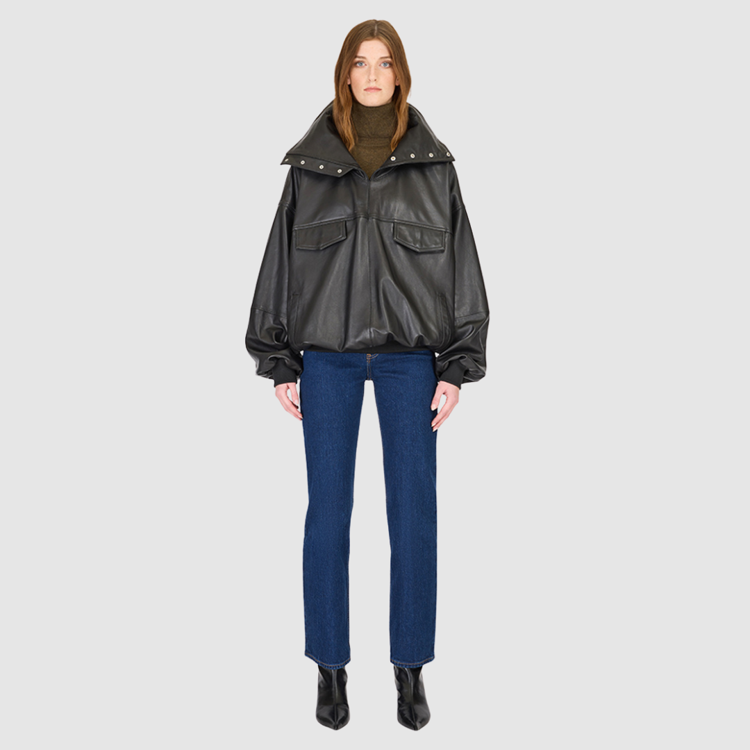 The Realm Black Leather Anorak Jacket is a modern interpretation of the classic anorak, elevated in luxury leather for a bold yet versatile statement. Designed with an oversized silhouette, it features a structured funnel neck collar and a concealed half-zip placket with gunmetal snap closures. Voluminous balloon sleeves and a cinched hem bring sculptural dimension, while functional flap pockets add everyday utility. A fusion of designer craftsmanship and contemporary outerwear design