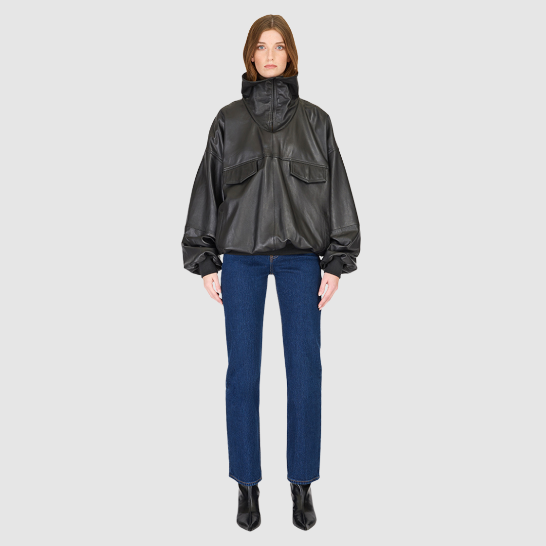 The Realm Black Leather Anorak Jacket is a modern interpretation of the classic anorak, elevated in luxury leather for a bold yet versatile statement. Designed with an oversized silhouette, it features a structured funnel neck collar and a concealed half-zip placket with gunmetal snap closures. Voluminous balloon sleeves and a cinched hem bring sculptural dimension, while functional flap pockets add everyday utility. A fusion of designer craftsmanship and contemporary outerwear design