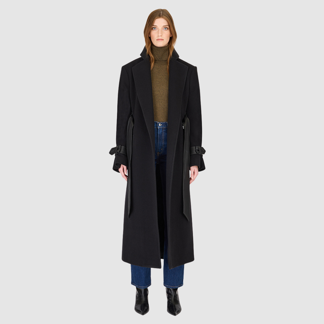 The EVERLY Black Wool Cashmere Blend Long Coat combines luxurious materials with structured, architectural design. Crafted from an Italian wool-cashmere blend, it features a leather tie belt at the waist to define the silhouette, along with structured shoulders and a classic notch collar. Leather cuff straps, a leather storm panel at the back, and single welt leather side pockets add refined detailing, while the back vent ensures ease of movement. 