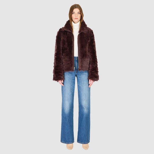 This cropped teddy jacket features a reversible design, with wool-out on one side and nappa-out on the other. The relaxed shoulder, spread collar, and slash side pockets provide comfort and functionality, while the front zip closure adds a practical touch.