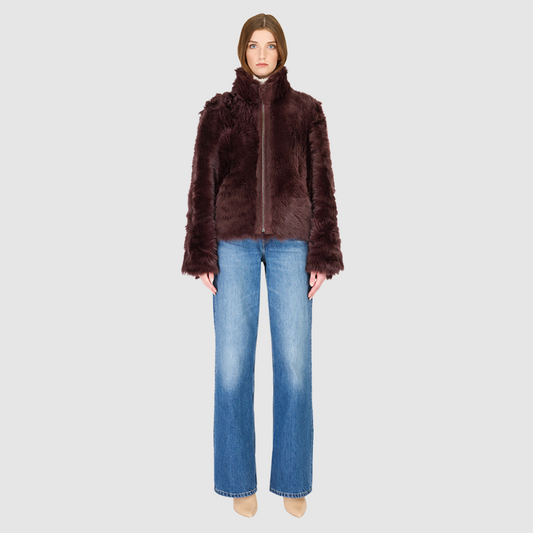 This cropped teddy jacket features a reversible design, with wool-out on one side and nappa-out on the other. The relaxed shoulder, spread collar, and slash side pockets provide comfort and functionality, while the front zip closure adds a practical touch.