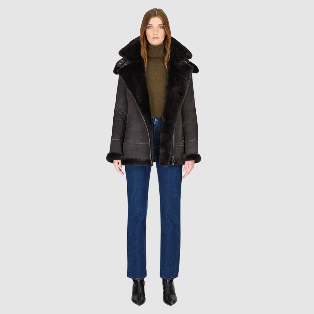 The MARTINA Jacket is a heritage-inspired medium-length shearling moto crafted in black vintage suede&nbsp;leather with curly wool collar and trims for elevated texture and warmth. Its relaxed fit with dropped shoulders ensures a modern, effortless silhouette, while the removable hood adds versatility for changing weather. Practical hidden interior pockets, exterior side zip pockets, and an asymmetrical front zip closure combine function with luxe design, making MARTINA ideal for après-ski layering