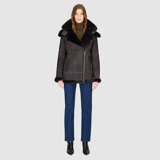 The MARTINA Jacket is a heritage-inspired medium-length shearling moto crafted in black vintage suede&nbsp;leather with curly wool collar and trims for elevated texture and warmth. Its relaxed fit with dropped shoulders ensures a modern, effortless silhouette, while the removable hood adds versatility for changing weather. Practical hidden interior pockets, exterior side zip pockets, and an asymmetrical front zip closure combine function with luxe design, making MARTINA ideal for après-ski layering