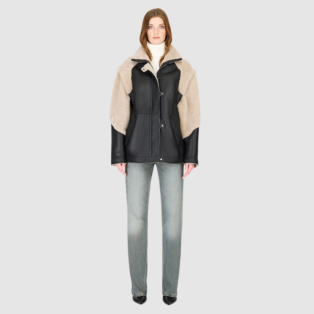 The SOLO Black Beige Moto Jacket redefines versatility with a bold mixed-media design that fuses supple nappa leather and plush curly wool shearling. Designed with a relaxed fit through the shoulders, arms, and torso, this statement jacket easily converts into a vest with removable zip sleeves for year-round styling. The curly wool collar, shoulders, and sleeves bring rich texture, while the stand collar and moto-inspired hardware emphasize its urban edge. 