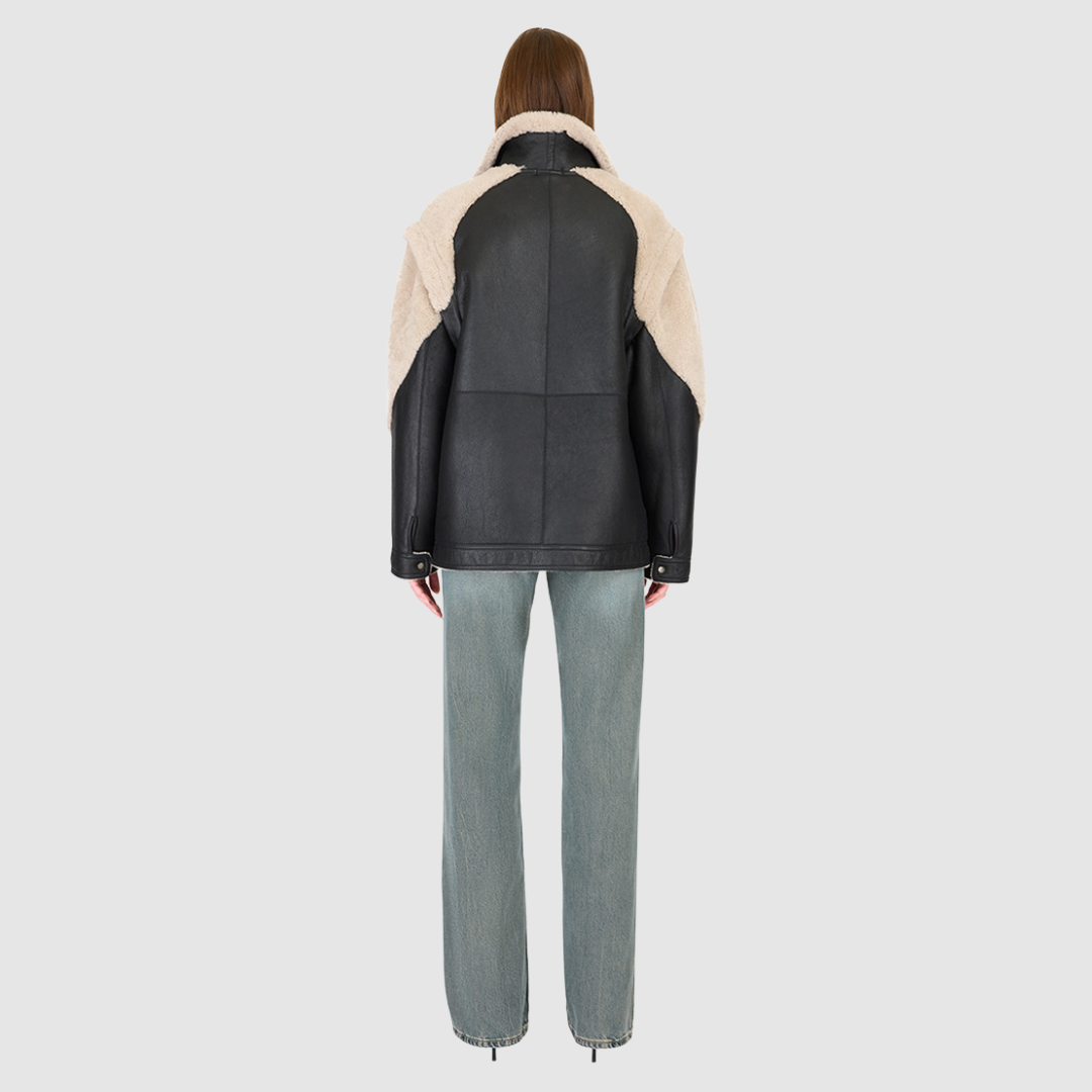 The SOLO Black Beige Moto Jacket redefines versatility with a bold mixed-media design that fuses supple nappa leather and plush curly wool shearling. Designed with a relaxed fit through the shoulders, arms, and torso, this statement jacket easily converts into a vest with removable zip sleeves for year-round styling. The curly wool collar, shoulders, and sleeves bring rich texture, while the stand collar and moto-inspired hardware emphasize its urban edge. 