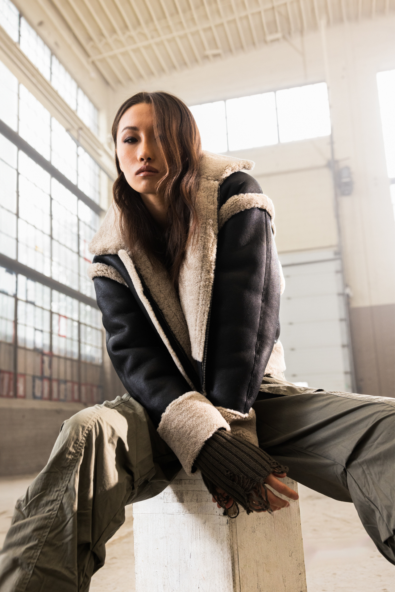 Discover our women's reversible oversized cropped nappa jacket, perfect for winter. It reverses to a cozy curly wool teddy, featuring a drop shoulder and dolman sleeve for comfort. Tapered at the hem, it includes single welt side pockets on the nappa side and slash pockets on the curly wool side. Complete with a front zip closure, this designer coat blends style and functionality, ideal for versatile seasonal wear.