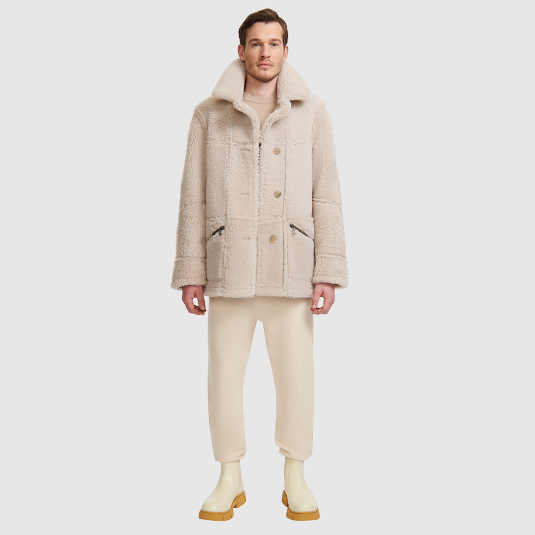 The Lyle Cement Reversible Shearling Jacket is a versatile mixed-media parka designed for modern layering and functionality. Crafted with contrast curly wool outer details, it features a slightly oversized fit with a regular shoulder for comfort. Oversized patch pockets and a button front closure provide practical utility, while the reversible design allows two distinct styling options in one piece.