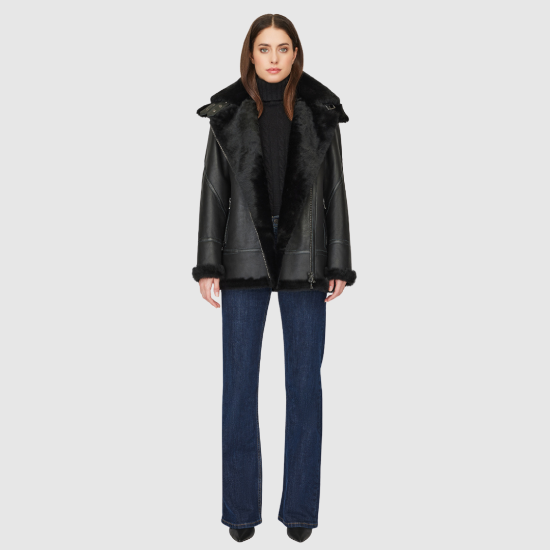 The HiSO Martina Jet Silky Shearling Moto features a relaxed nappa leather design with an Ironed wool collar and trims. Drop shoulders add a touch of style, while a detachable hood provides versatility. The asymmetrical front zip closure and exterior zip pockets add functionality, with hidden inside pockets for added convenience.