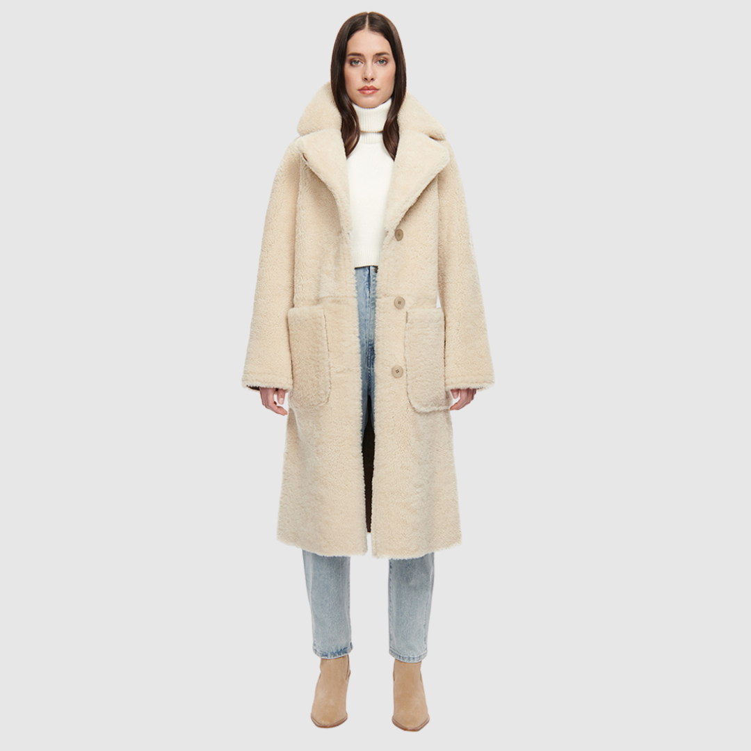 Suede curly wool shearling Vintage inspired reversible notch collar Reverses to curly wool teddy Relaxed dropped shoulder 3 button closure Tie belt at waist Zip pockets on suede side, reverses to patch pockets on teddy side