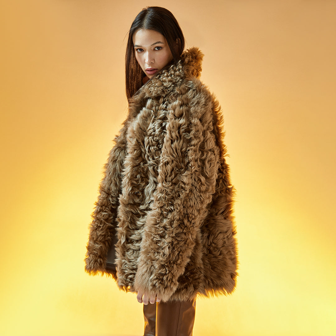 This curly reversible shearling coat makes for a warm and stylish winter coat. Made of exceptionally warm and soft Spanish shearling,  this coat features a soft Nappa exterior, which reverses to a decadent curly wool toscana sheepskin side.  Either way you wear it, a stunning, timeless look. Button front, with slip pockets on either side.